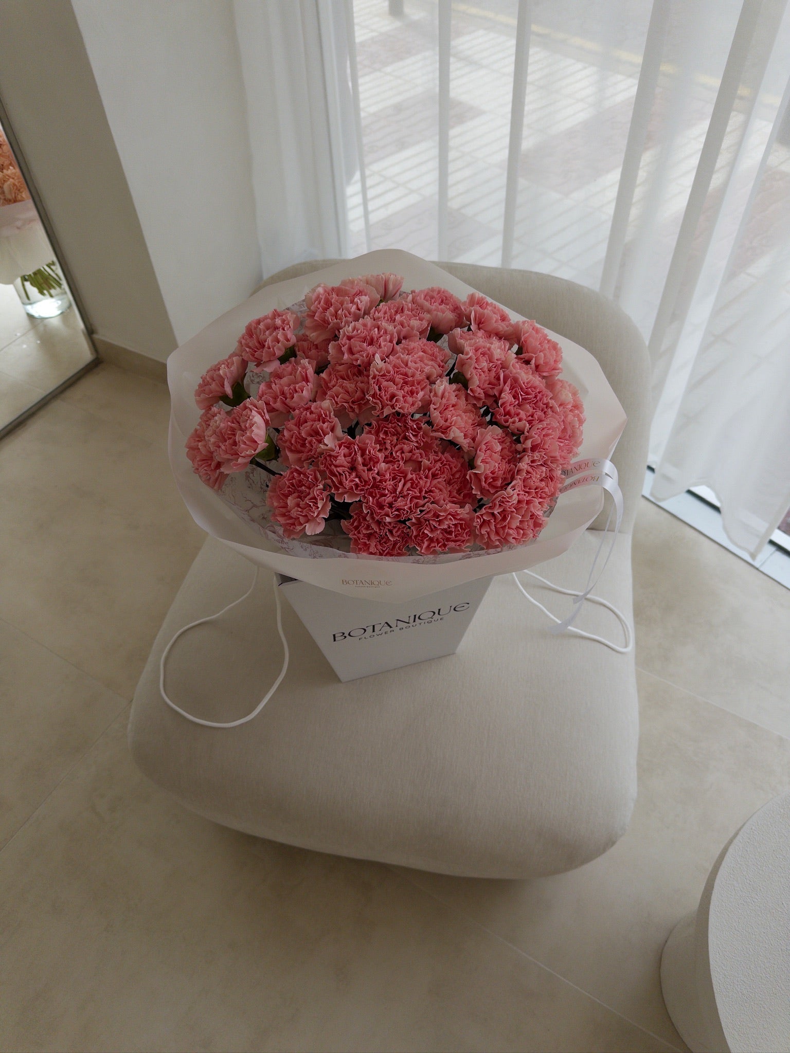 Bouquet of pink flowers in a white box on a white surface with a blurred background